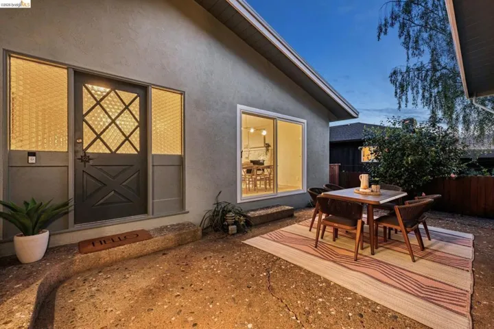 Back of house with stucco siding, outdoor dining space, and a patio