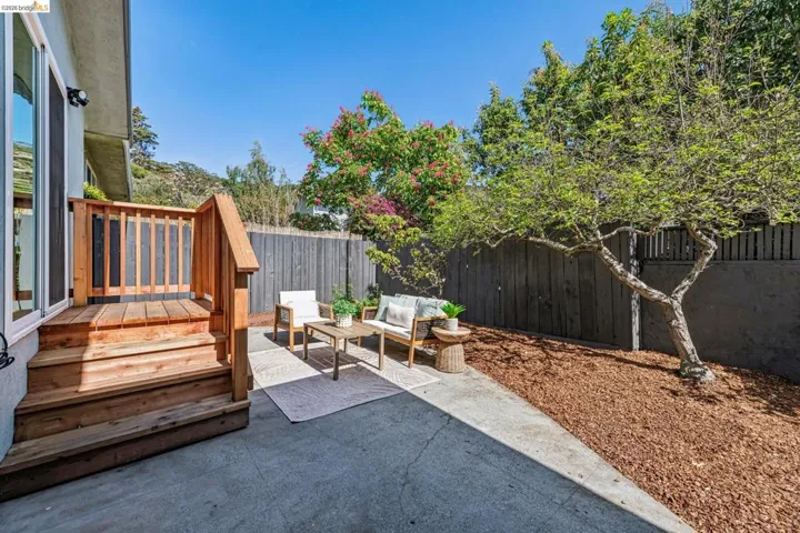 Fenced backyard featuring a wooden deck, outdoor furniture, and a patio area