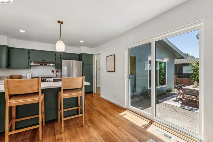 Kitchen featuring green cabinetry, a peninsula, light countertops, light wood-style flooring, and stainless steel appliances