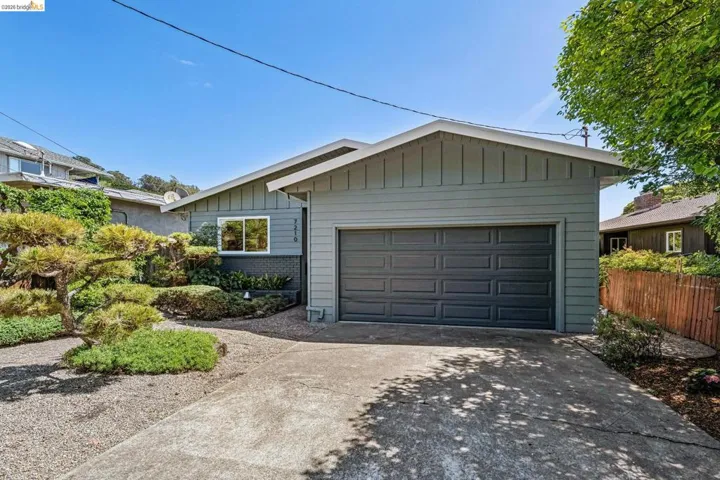 Single story home with brick siding, concrete driveway, a garage, and board and batten siding