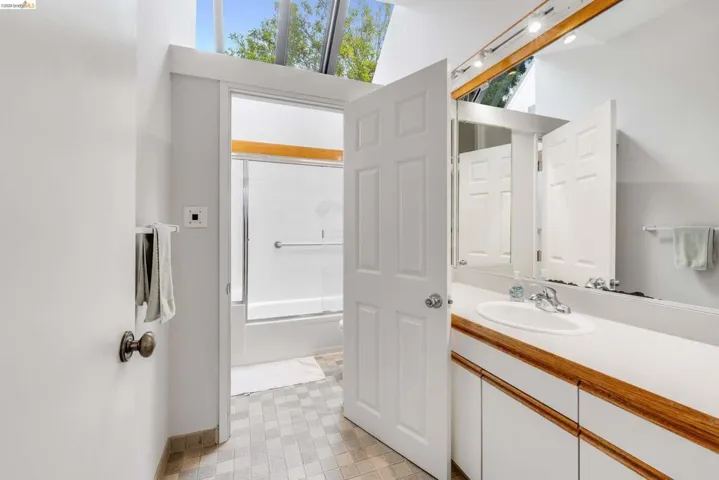 Bathroom with vanity, shower / bath combination with glass door, and light floors