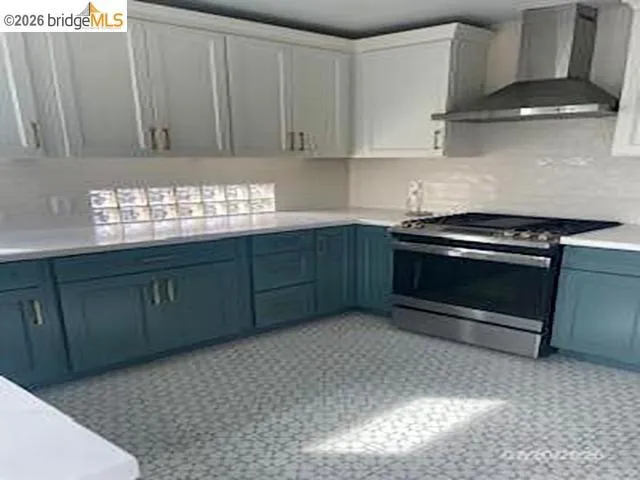 Kitchen featuring stainless steel range with gas stovetop, decorative backsplash, and two tone cabinetry