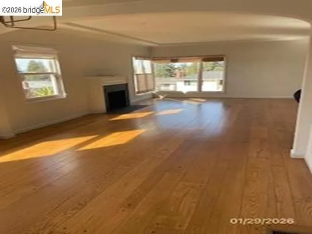 Unfurnished living room featuring a fireplace, wood-type flooring, and a chandelier