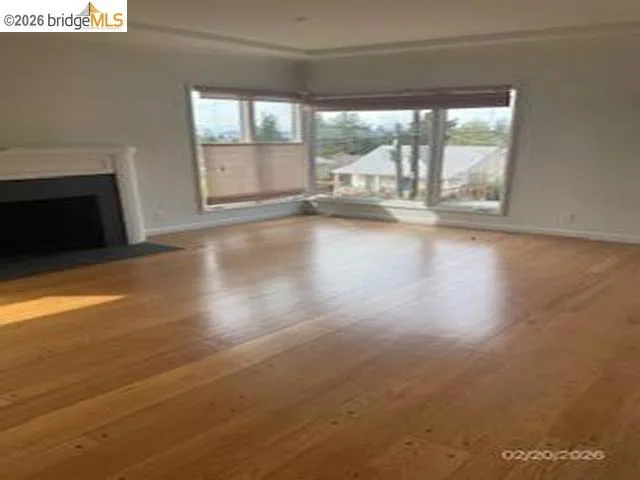 Unfurnished living room featuring a fireplace with flush hearth, plenty of natural light, and hardwood / wood-style flooring