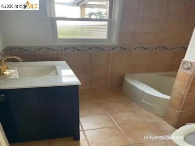 Full bath featuring vanity, tile walls, and light tile patterned flooring