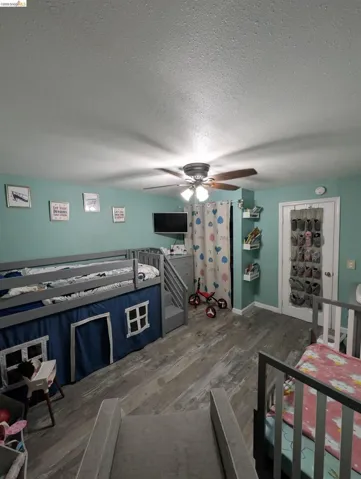 Bedroom featuring dark wood finished floors, a ceiling fan, and a textured ceiling