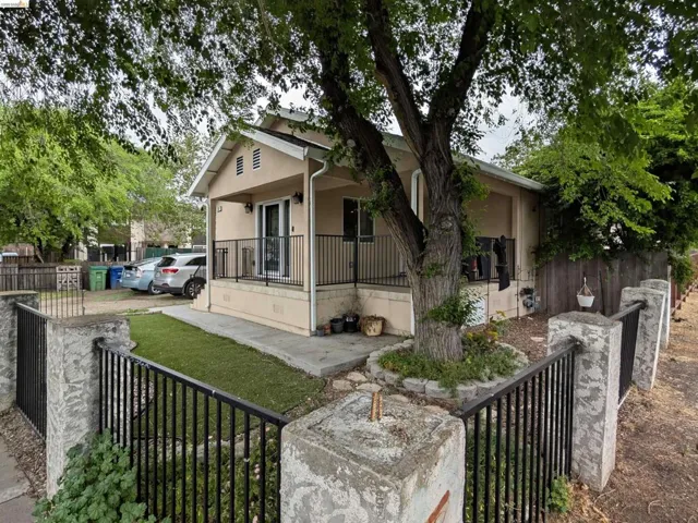 View of front of house with covered porch, a fenced front yard, and stucco siding