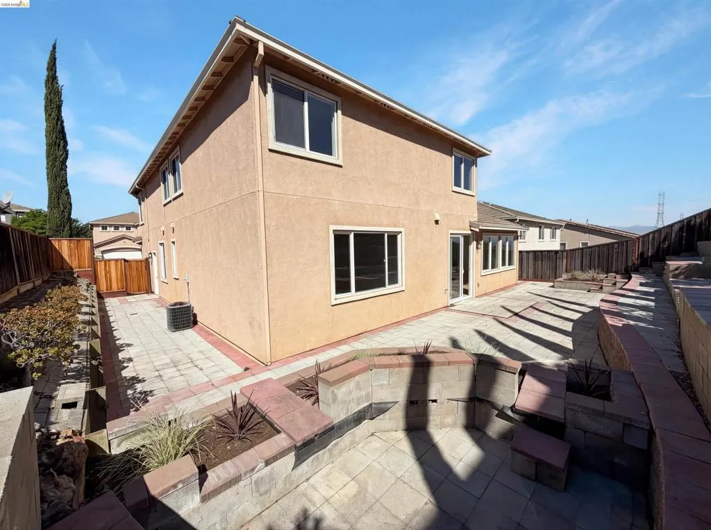 Rear view of house with a fenced backyard, stucco siding, and a patio