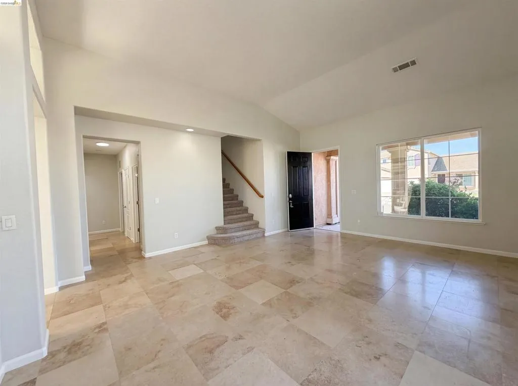 Spare room with stairway and lofted ceiling