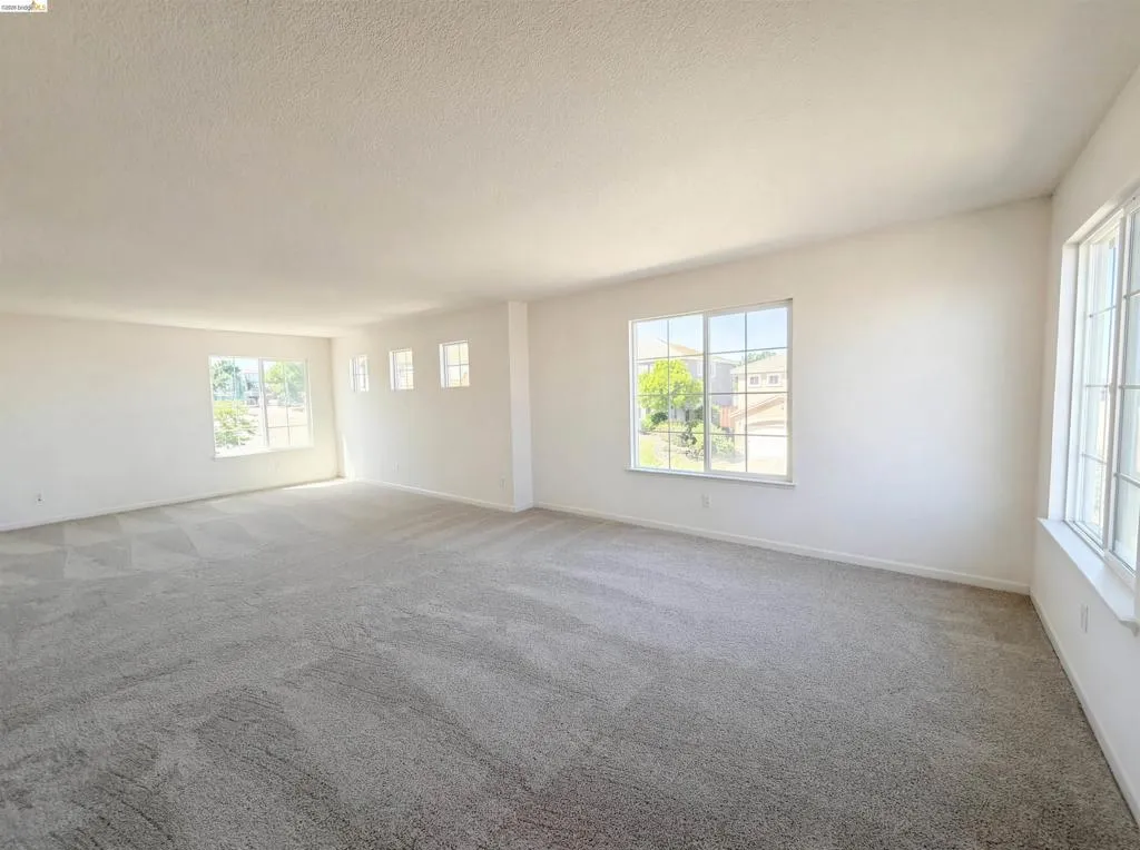 Empty room with light carpet and a textured ceiling