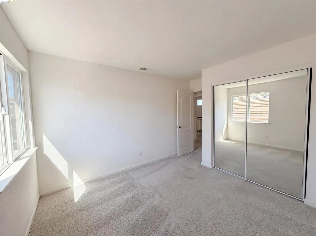 Unfurnished bedroom with light carpet and a closet