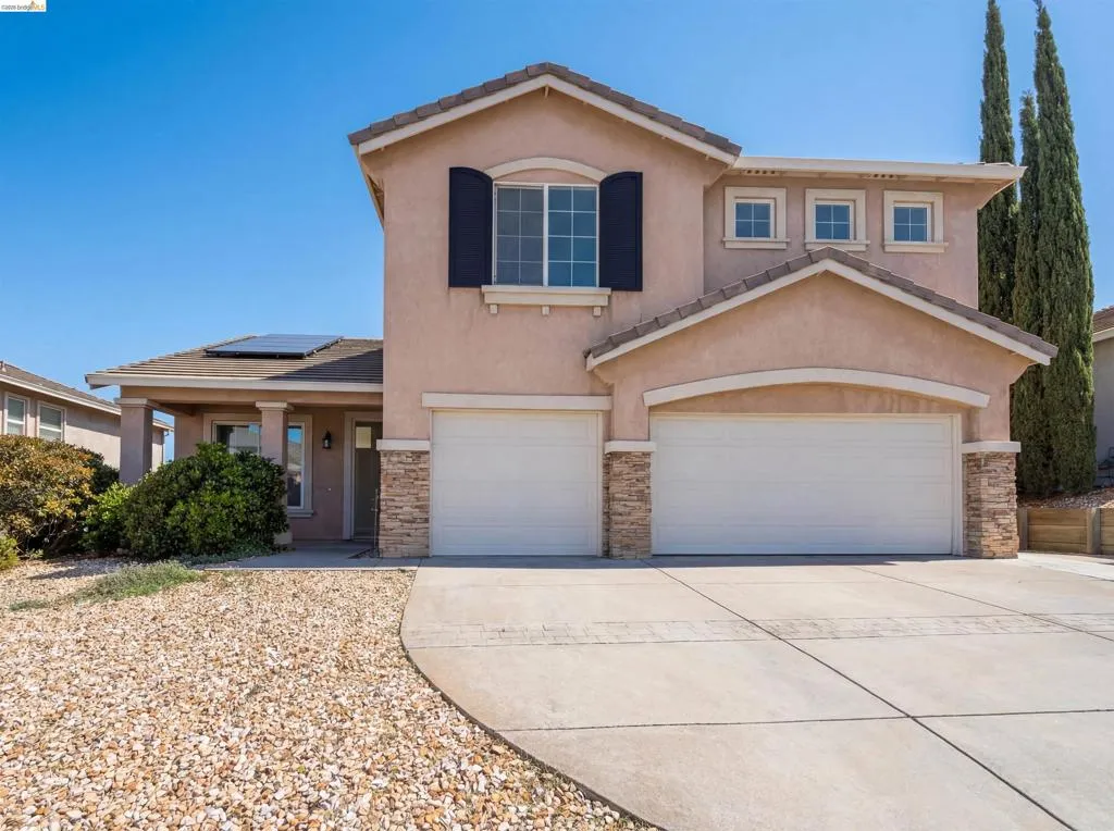 View of front of house with stucco siding, stone siding, concrete driveway, and a garage