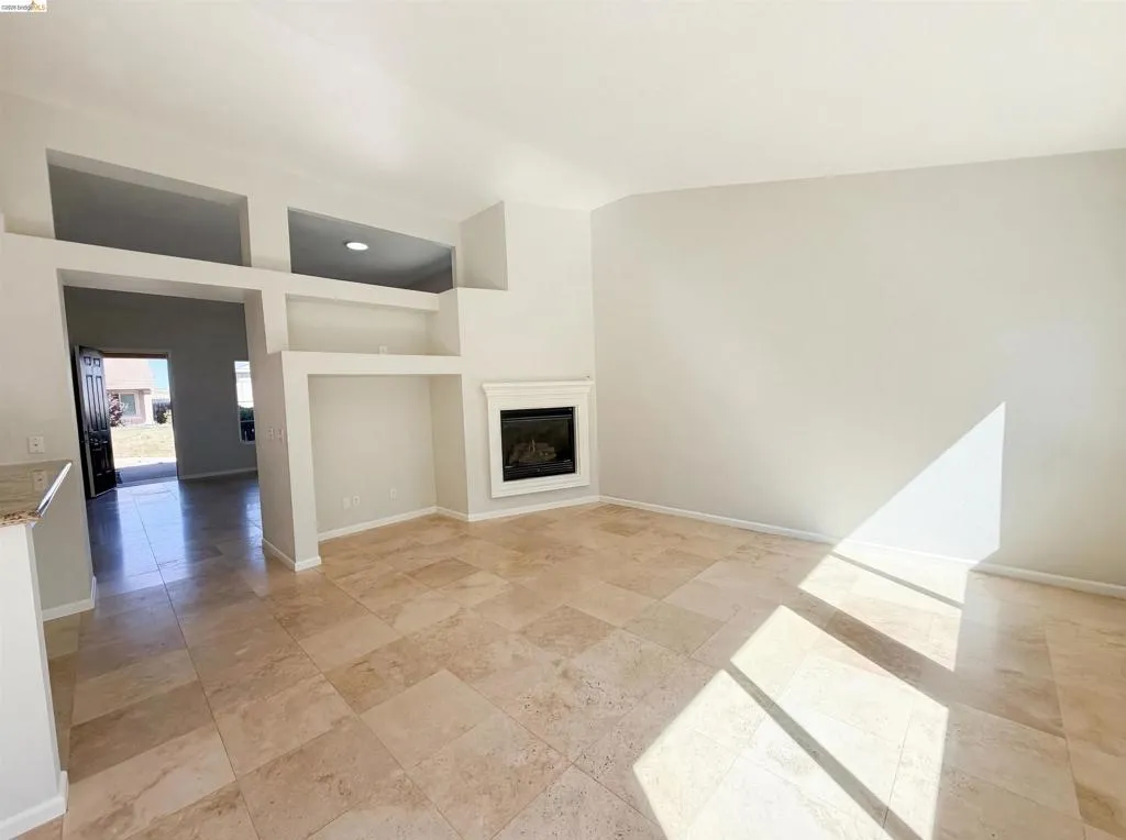 Unfurnished living room with a glass covered fireplace and light stone finish flooring
