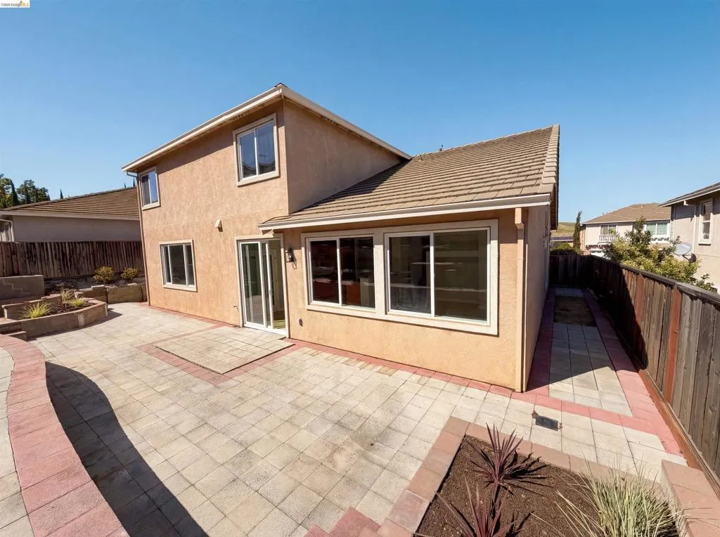 Back of property featuring a fenced backyard, a patio area, and stucco siding