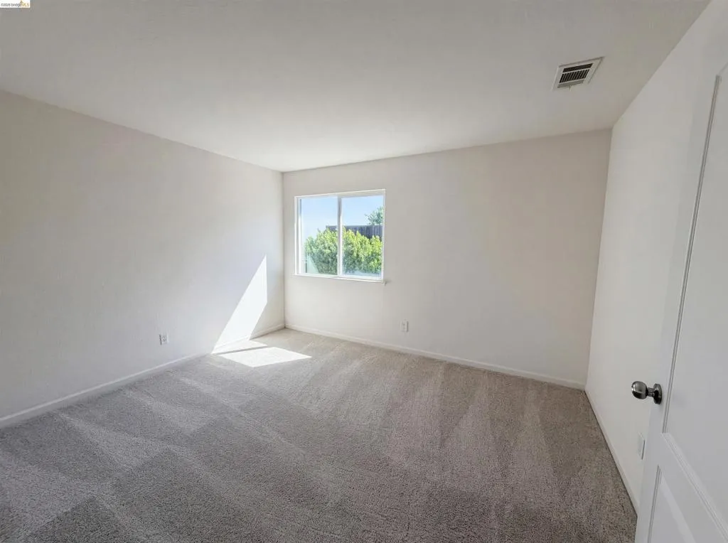 Empty room with light colored carpet and baseboards