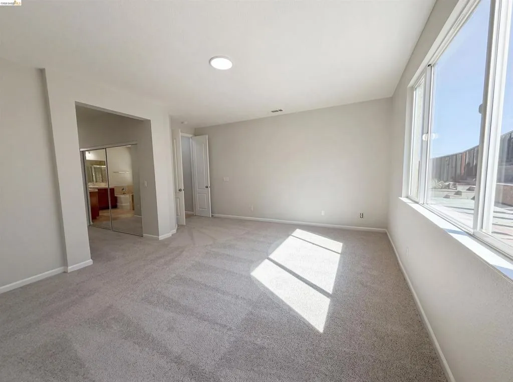 Unfurnished bedroom featuring a closet, light carpet, and ensuite bathroom