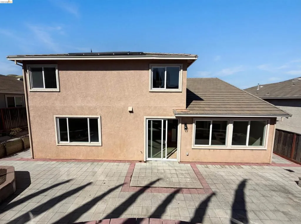Rear view of house featuring stucco siding, a patio, and solar panels