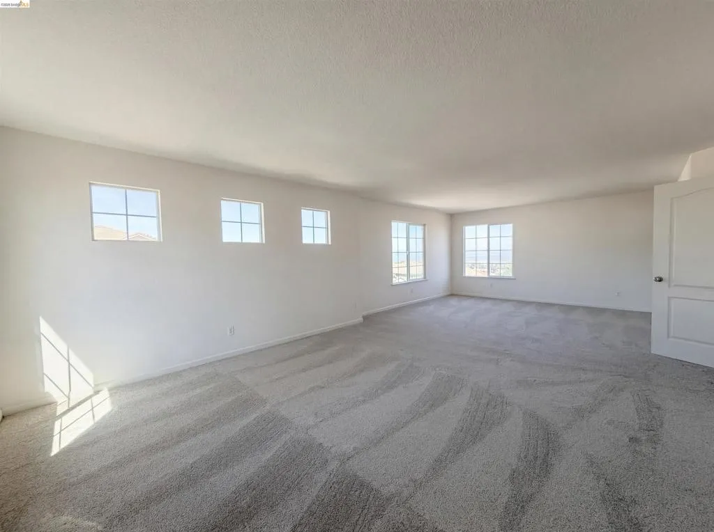 Unfurnished room featuring light carpet and baseboards