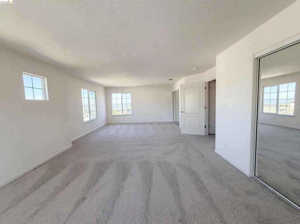 Spare room featuring light colored carpet, healthy amount of natural light, and a textured ceiling