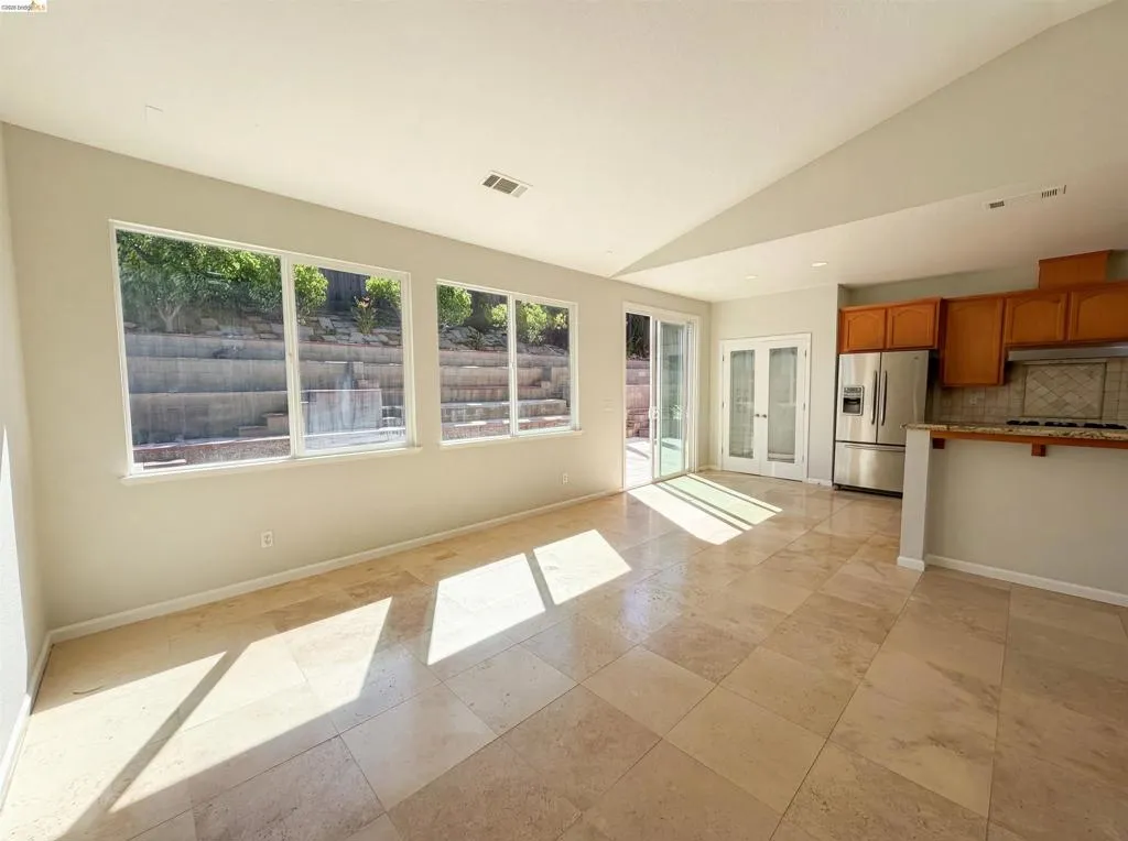 Kitchen featuring wood finish cabinets, stainless steel refrigerator with ice dispenser, vaulted ceiling, tasteful backsplash, and french doors