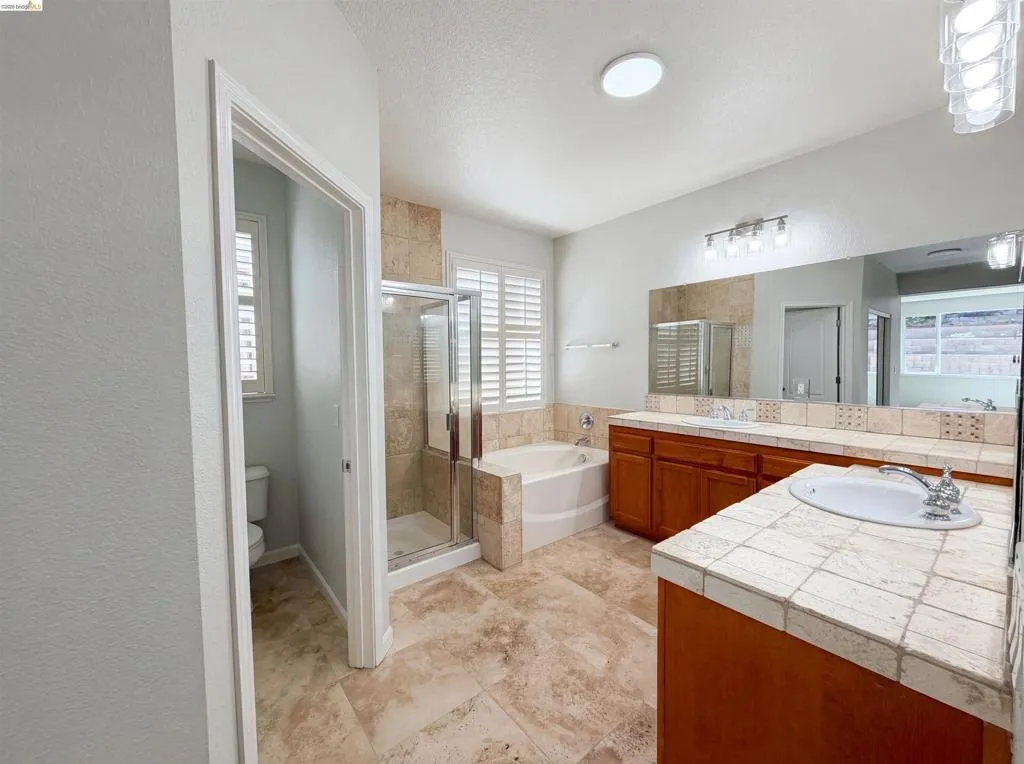 Full bathroom with a stall shower, a bath, double vanity, and a textured ceiling