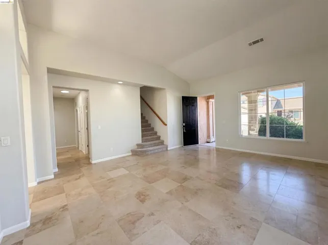 Spare room with stairway and lofted ceiling