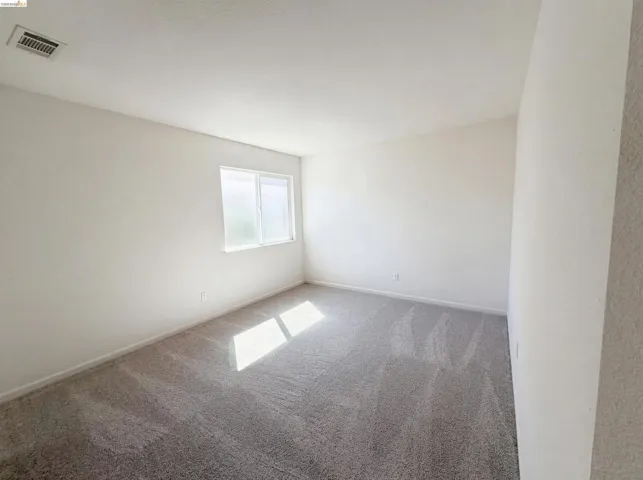 Empty room with light colored carpet and baseboards