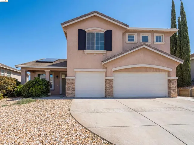 View of front of house with stucco siding, stone siding, concrete driveway, and a garage