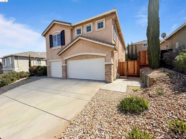 Traditional home with stone siding, driveway, stucco siding, and a garage