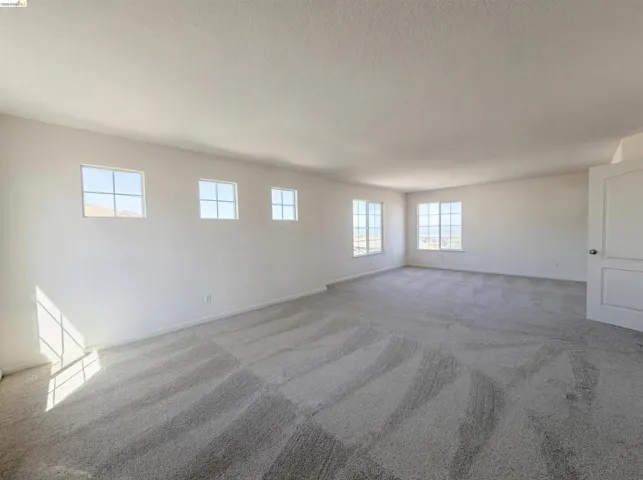 Unfurnished room featuring light carpet and baseboards
