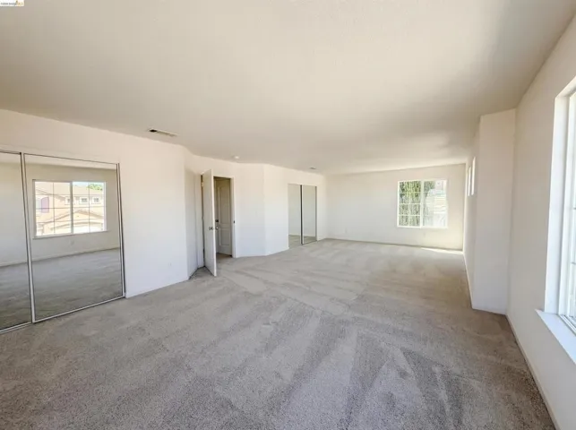Unfurnished living room featuring light colored carpet and plenty of natural light