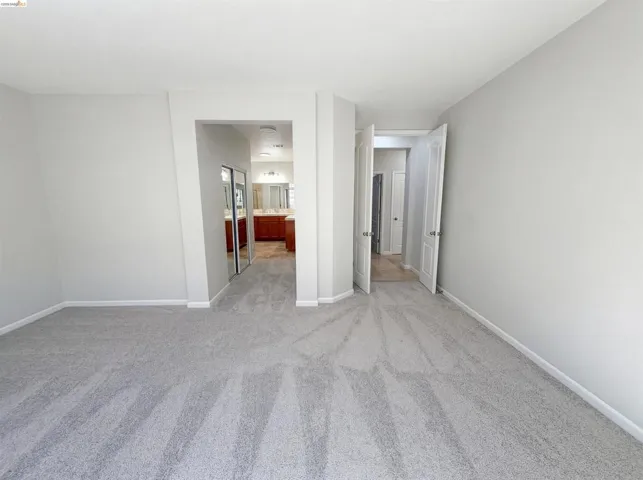 Empty room with light colored carpet and baseboards