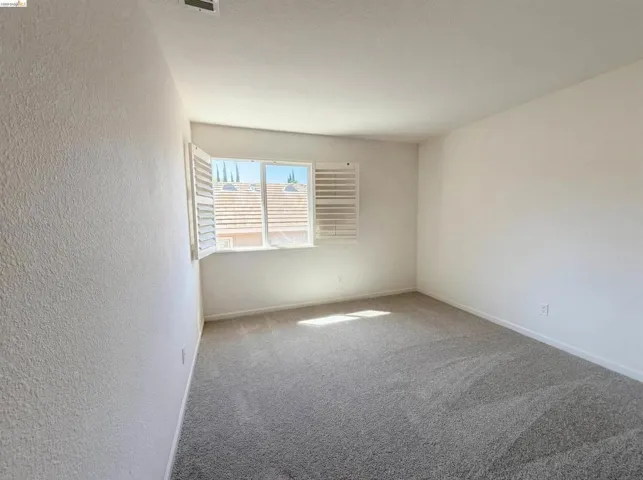 Unfurnished room with carpet and a textured wall