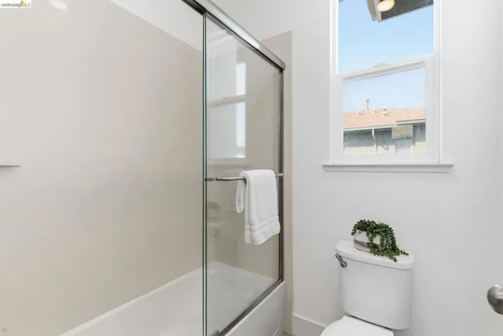 Bathroom featuring toilet and bath / shower combo with glass door