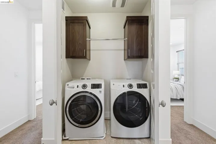 Laundry area with light colored carpet, washer and dryer, and cabinet space