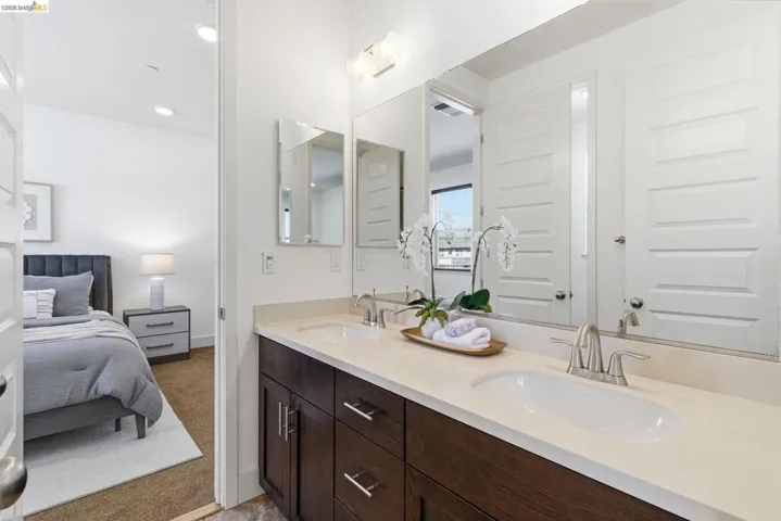 Ensuite bathroom with double vanity and light carpet