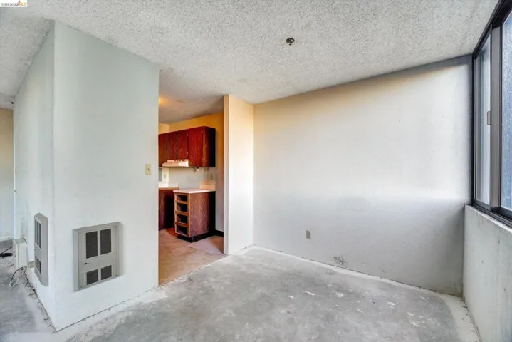Unfurnished living room with unfinished concrete flooring, heating unit, and a textured ceiling