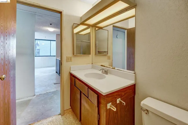 Bathroom with a textured wall, vanity, and unfinished concrete floors