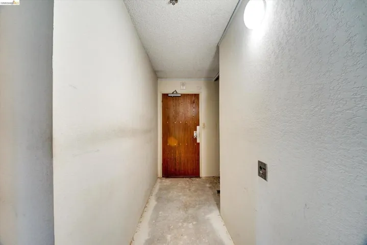 Hallway with unfinished concrete flooring, a textured ceiling, and a textured wall