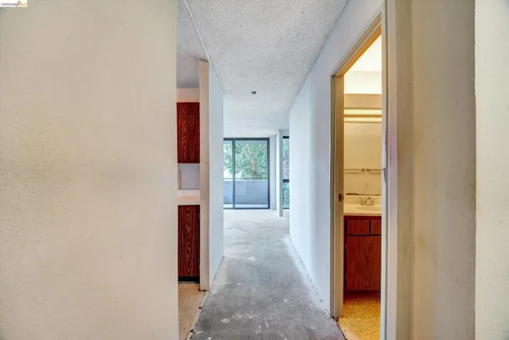 Hall with concrete flooring, a textured ceiling, and a textured wall