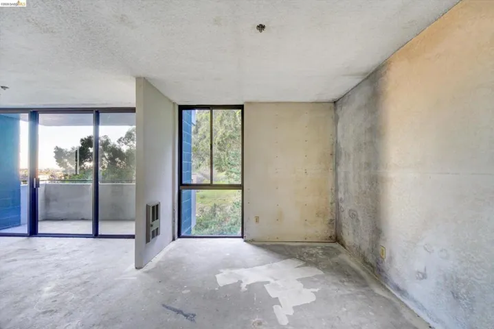 Unfurnished room featuring unfinished concrete floors, heating unit, and a textured ceiling