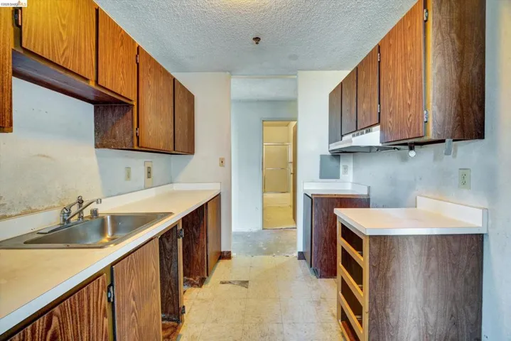 Kitchen featuring light countertops, a textured ceiling, and wood finish cabinets