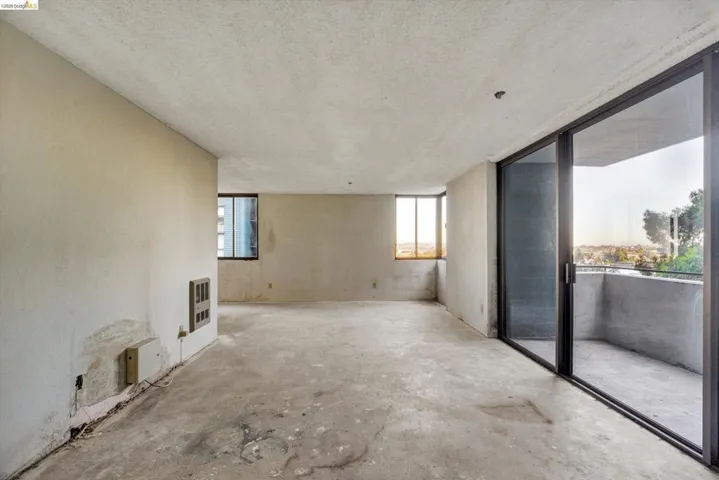 Unfurnished living room featuring unfinished concrete floors, a textured ceiling, plenty of natural light, and heating unit