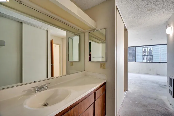 Bathroom with concrete flooring, a textured ceiling, and vanity