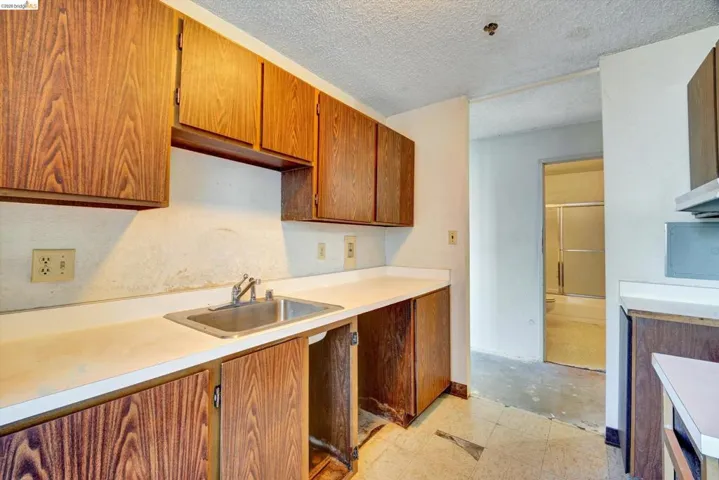 Kitchen with light countertops, wood finish cabinetry, and a textured ceiling