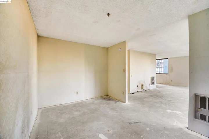 Unfurnished room featuring concrete floors, heating unit, and a textured ceiling