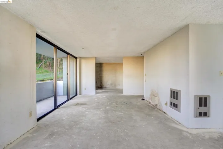 Unfurnished living room featuring heating unit, concrete floors, and a textured ceiling