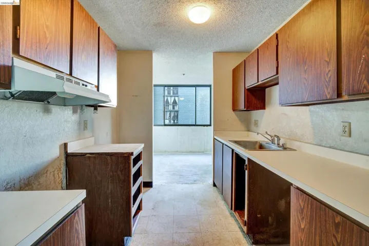 Kitchen featuring a textured ceiling, light countertops, and wood finish cabinetry