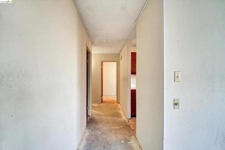 Hallway with unfinished concrete flooring and a textured ceiling