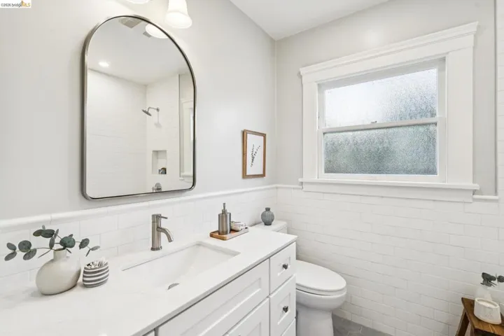Full bathroom featuring wainscoting, vanity, tile walls, and a tile shower